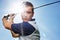 Taking golfing seriously. Young man in full swing during a round of golf against a blue sky.