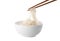 Taking rice noodles with chopsticks from bowl on white background