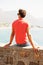 Taking time to discover tranquility. Rearview of a young man sitting on a wall overlooking the sea.