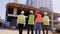 Taking video from the back of a group multiethnic diverse specialists at construction site they wearing safety helmets