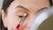 Taking video closeup adult woman using makeup brush to apply some makeup products on her eyes while holding a small