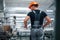 Taking the window. Industrial worker indoors in factory. Young technician with orange hard hat