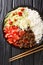 Takoraisu Okinawan Taco Rice with ground beef, vegetables, cheese and sauce close-up in a bowl. vertical top view