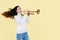 A talented Asian woman playing a trumpet, standing against an isolated yellow background