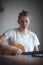 Talented boy playing a wooden acoustic guitar in a lighted room. Blonde Man aged 20-29 strums guitar and sings from hymn book on