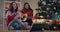 Talented Caucasian musician playing guitar singing with friend sitting at Christmas tree indoors. Portrait of two happy