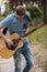 Talented guitarist playing forest hiking concept.