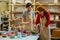 Talented long-haired woman in apron using paintbrush for decorating