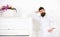Talented musician concept. Man with beard in bathrobe enjoys morning while standing near piano. Man serious stands and