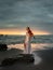 Talented woman with violin on the beach. Music and art concept. Slim girl wearing long white dress and playing violin in nature.