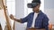 Talented young latin man artist engrossed in painting class, drawing art masterpiece using futuristic virtual reality glasses