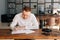 Talented young man wearing casual clothing writing musical notes with pen on paper sheet music