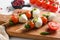 Talian food - caprese salad - skewer with tomato, mozzarella and basil, pesto sauce, mediterranean diet concept on old chopping