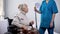 Talkative old lady in wheelchair gossiping with hospital janitor, loneliness