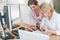 Talking with each other. Two female stock brokers in formal wear is working in the office by pc