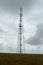 Tall aerial radio and cell phone antenna on a coastal meadow under an overcast sky