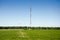 Tall antenna and wind Turbine in a green level field and deep bl