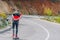 Tall athlete riding his longboard fast and steady downhill while wearing red t-shirt and black jeans