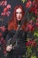 Tall beautiful red head girl wearing black leather outfit holding a fantasy sword surrounded with autumn color leaves foliage