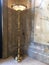 Tall brass light stand with marble wall and floor.