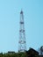 A tall cell tower rises above the rooftops of private houses against a blue sky