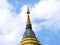Tall chedi with a colorful mosaic and golden, multi-tiered parasol at the top