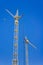 Tall construction tower crane in yellow against a bright blue sky