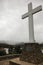 Tall cross on stone base overlooking lake on cloudy day