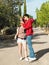 A tall dark-haired man takes off sunglasses entangled in blonde hair of a young woman with a camera