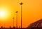 Tall electric pylon in the airport at sunset with an orange sky. Spotlights pole at the airfield. Energy support at the airport