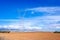 Tall electrical metal pylons over plowed farm fields and blue sky