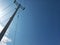 Tall Electricity Pole with Its Wires or Cables Against Clear Blue Sky Background