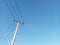 Tall Electricity Pole with Its Wires or Cables Against Clear Blue Sky Background