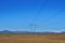 Tall electricity pylons leading high electric current with a high mountains and blue sky in the background in Iceland