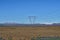 Tall electricity pylons leading high electric current with a high mountains and blue sky in the background in Iceland