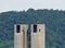 Tall factory chimneys with a background of a forested mountain