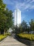 Tall Giant Single Skyscraper against blue sky among lush green trees