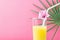 Tall Glass with Freshly Squeezed Pineapple Citrus Tropical Fruit Juice with Straw and Flower. Fuchsia Background Palm Tree Leaf