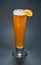 Tall glass of unfiltered white beer with a sclice of orange on it over a black background