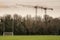 Tall goal post for Irish sports in a park and two tall cranes in the background. Training ground for camogie, hurling, rugby and