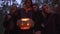 Tall handsome man holding halloween pumpkin with a light inside close up, three pretty girls standing near. People with
