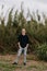 Tall and Handsome Young Man with Long Hair Pulled Back Modeling in Front of Very Tall Grass Outside in Nature