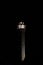 Tall illuminated lighthouse against a dark night sky