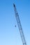Tall industrial crane with hook on clear blue sky
