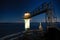Tall lighthouse with a metal bridge on the seashore with a beautiful night sky in the background