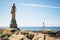 tall lighthouse statue near a coastal route
