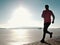 Tall man beach running at sunrise, frozen lake coastline