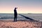 Tall man in black suit exercising and make stretching on stony beach at breakwater.