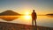 Tall man with sunglasses and dark cap is running on the beach at sunset. Silhouette of sport active man running at mountain lake