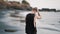 Tall man walks along beach with volcanic sand against ocean